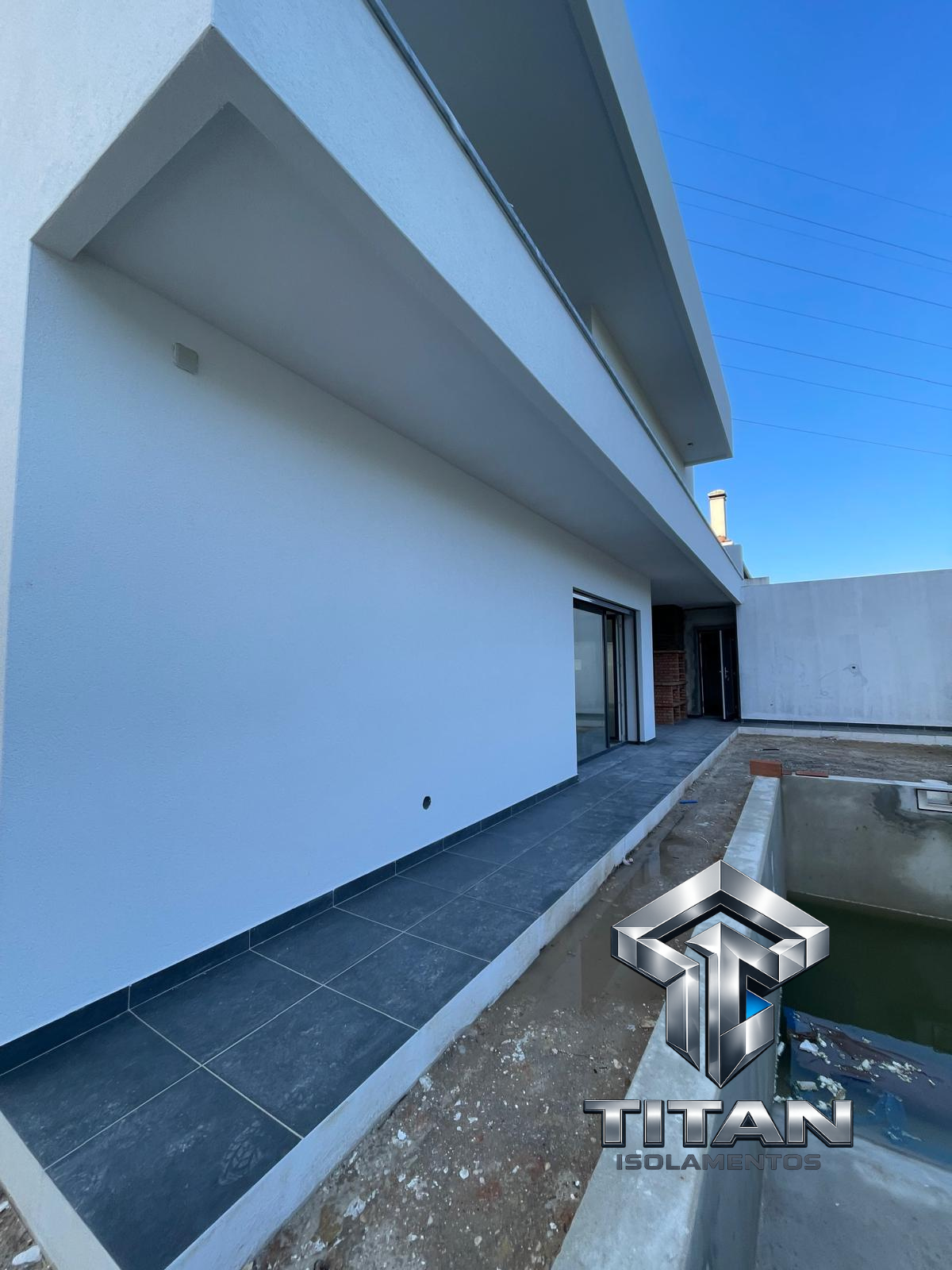 Fachada branca lateral de moradia com zona de piscina em construção